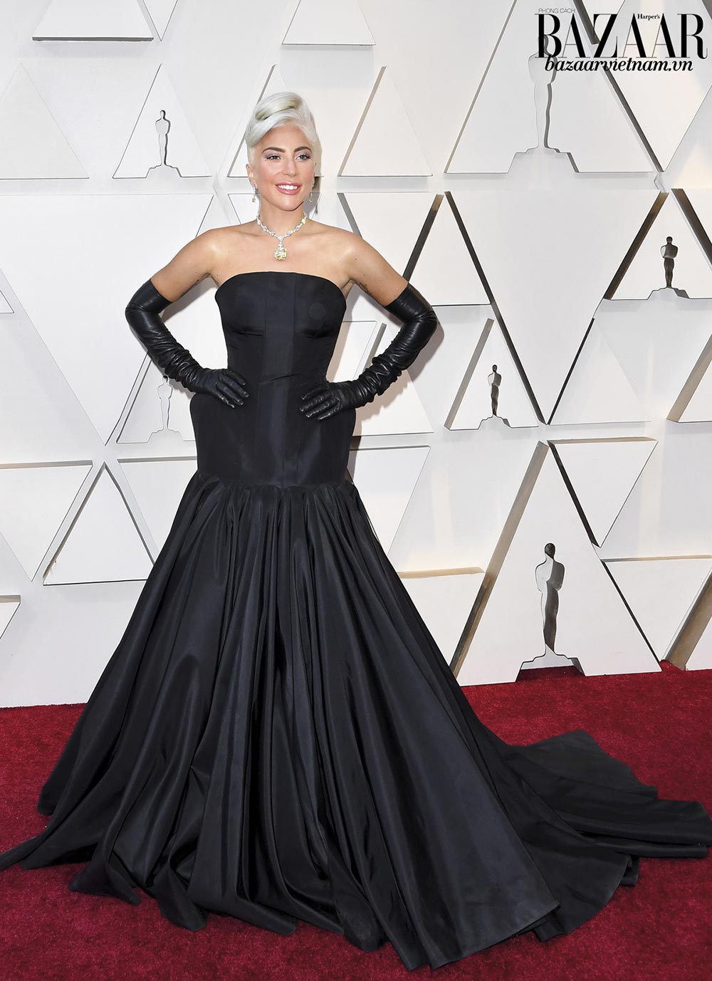 Lady Gaga tái hiện phong cách của biểu tượng Audrey Hepburn. Đầm đen của Alexander McQueen giúp nữ ca sỹ tôn mái tóc bạch kim và viên kim cương vàng của Tiffany & Co.